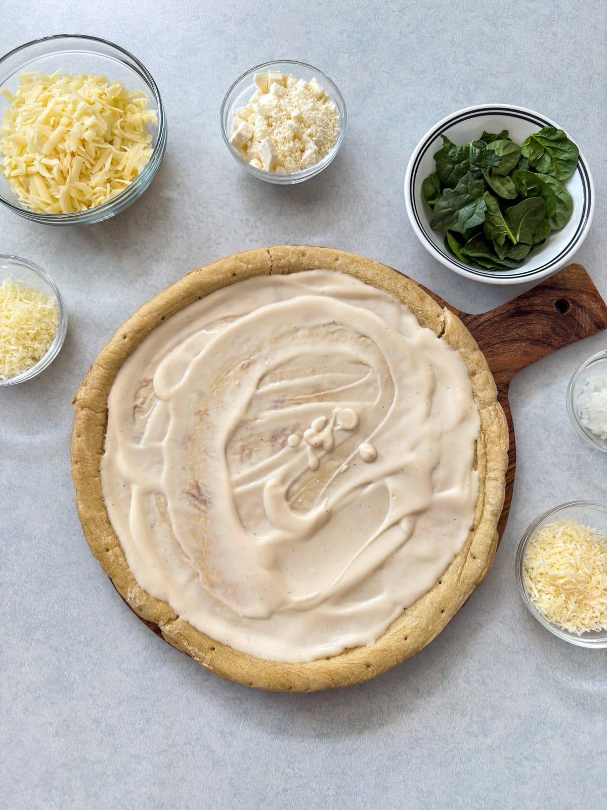 The alfredo sauce spread all over the unbaked pre-made pizza crust.