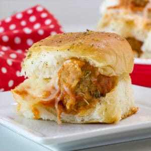 Feature image of the side view of one baked slider on a white plate.