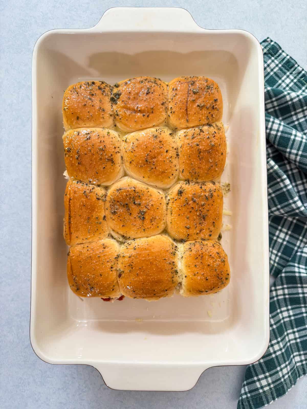 The unbaked sliders with the top added and then brushed with melted butter.