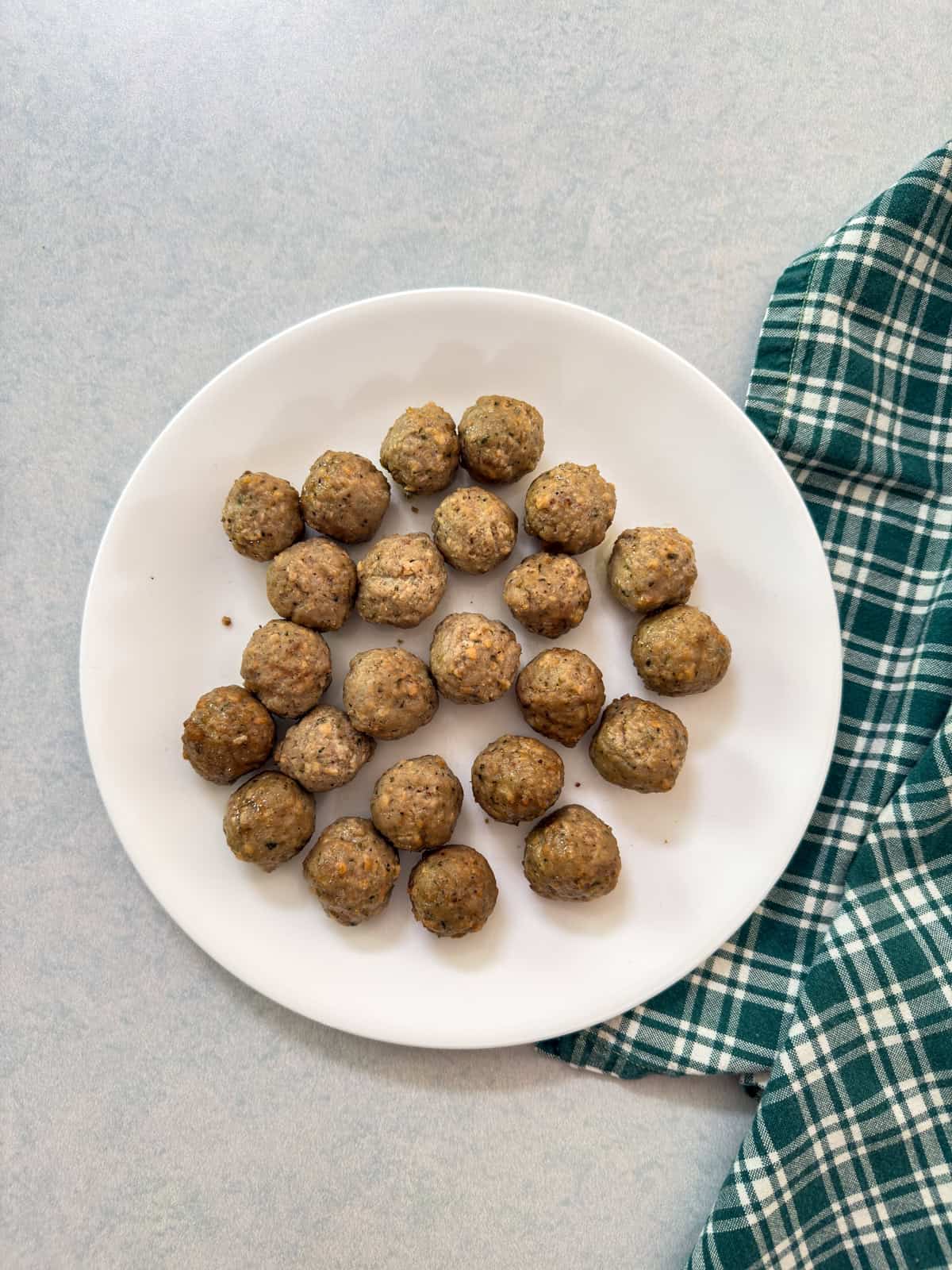The warmed meatballs on a plate after coming out of the microwave.