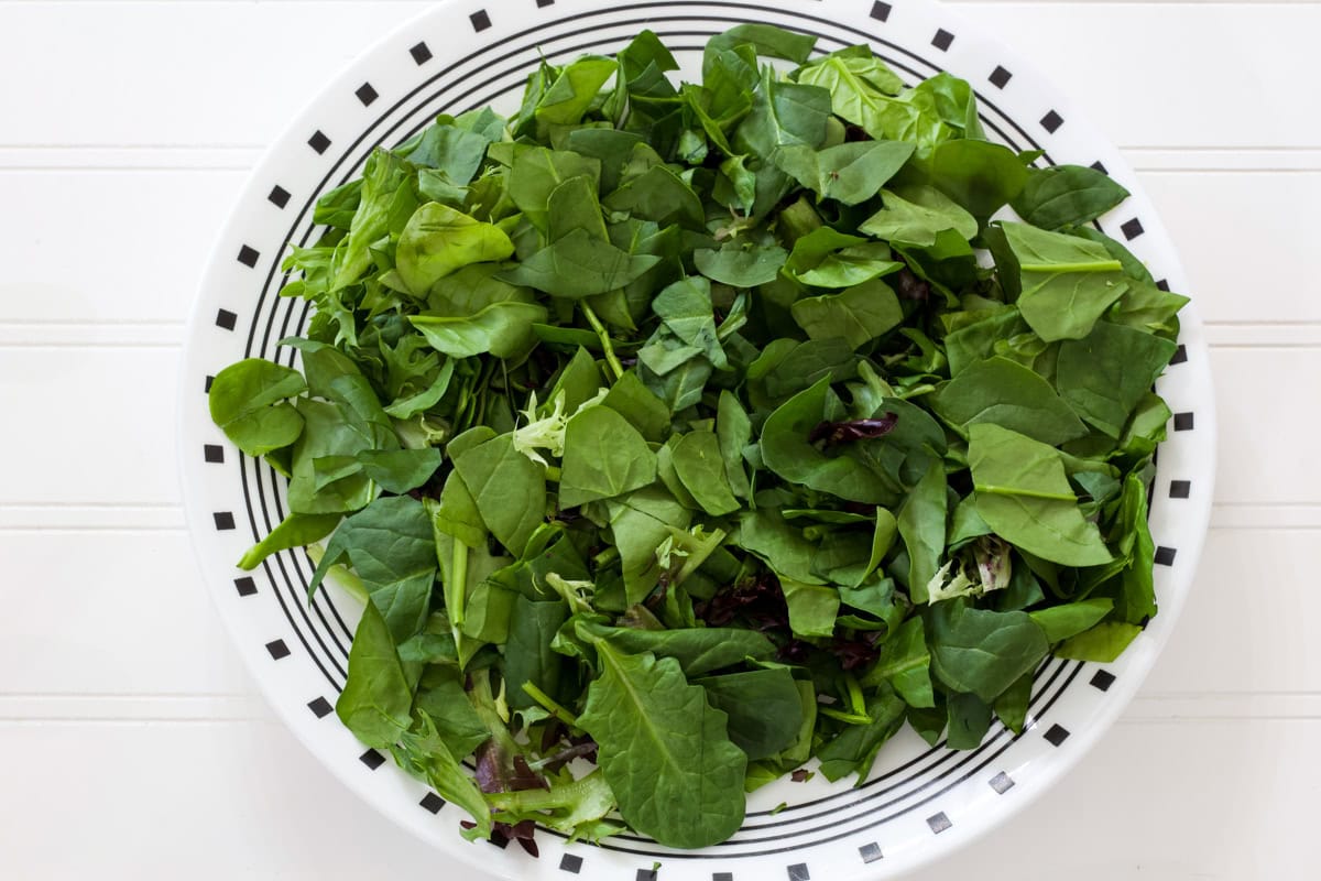The cut up mixed greens spread out on a dinner plate.