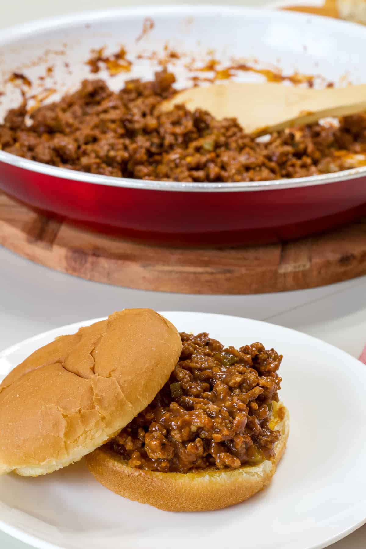 One sloppy joe with the top buns off center so the sloppy joe mixture is visible.