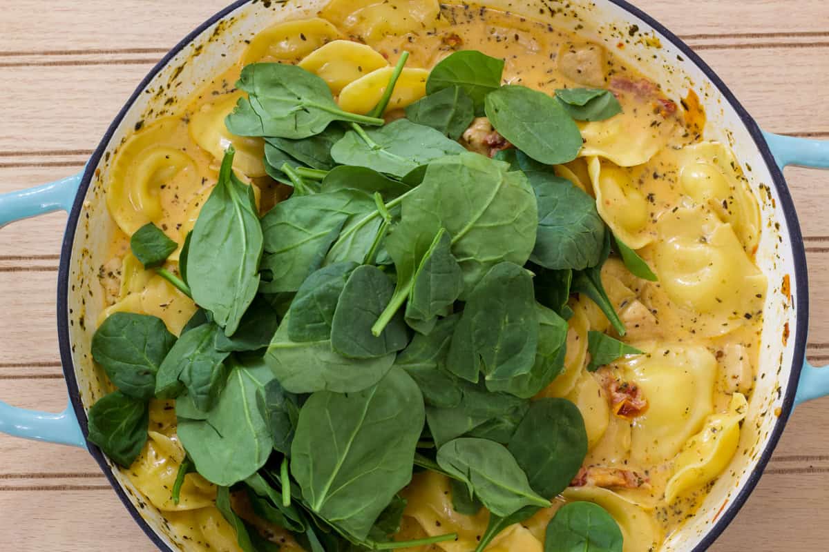 The dish with the cheese ravioli and spinach added before they are mixed in.