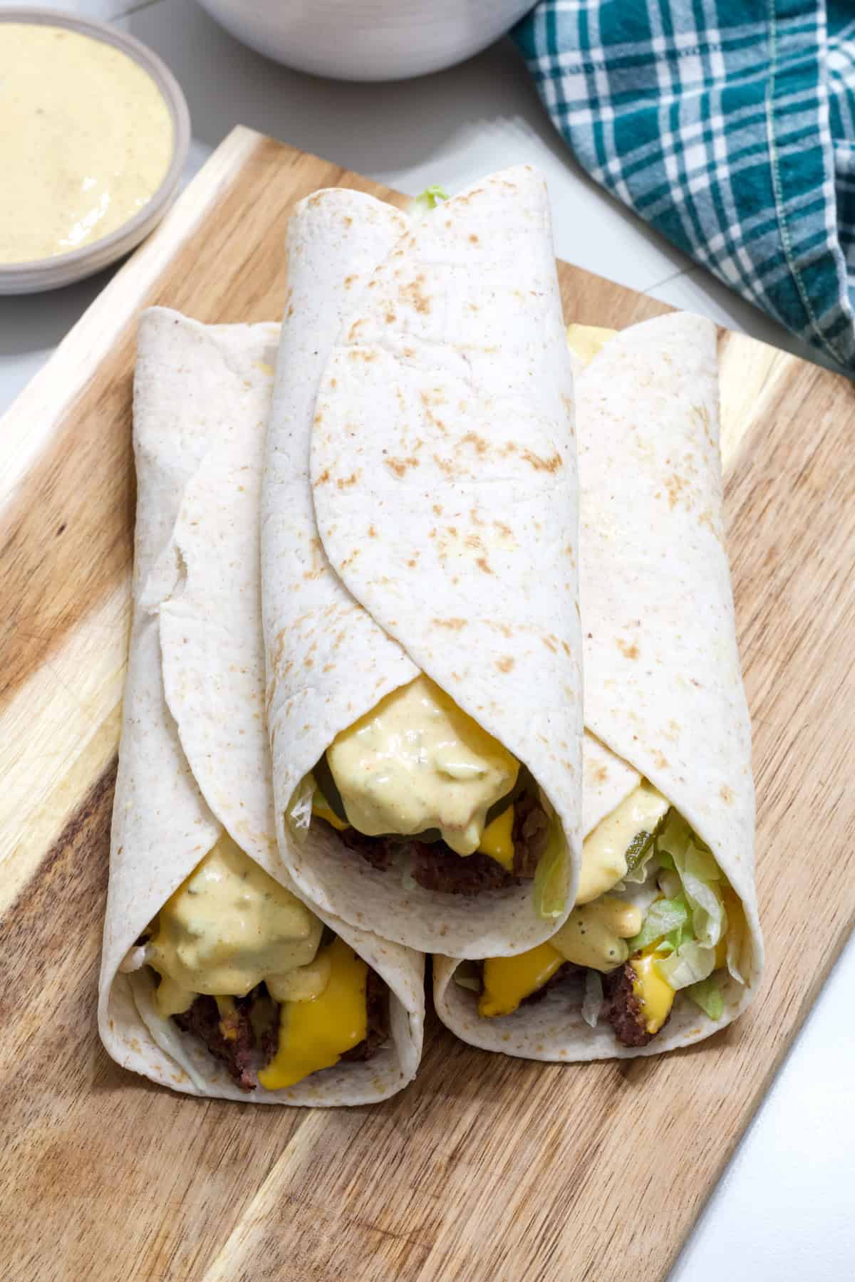 Three Big Mac Wraps on a wooden cutting board.