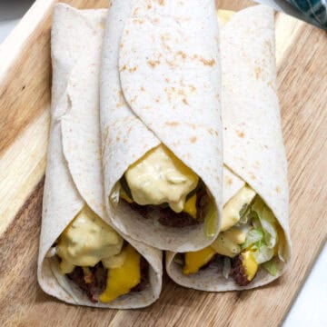 Feature image of the end of three big mac wraps on a wooden cutting board.