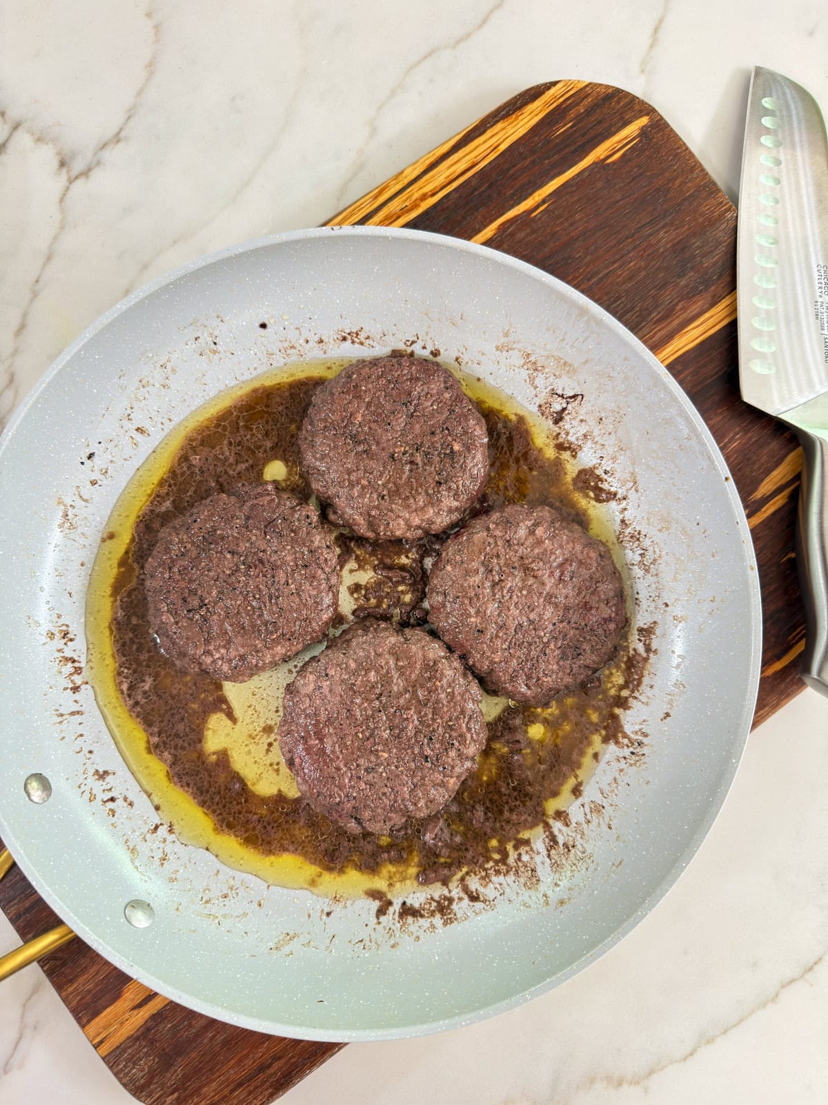 Four beef patties in the skillet after they've been cooked.