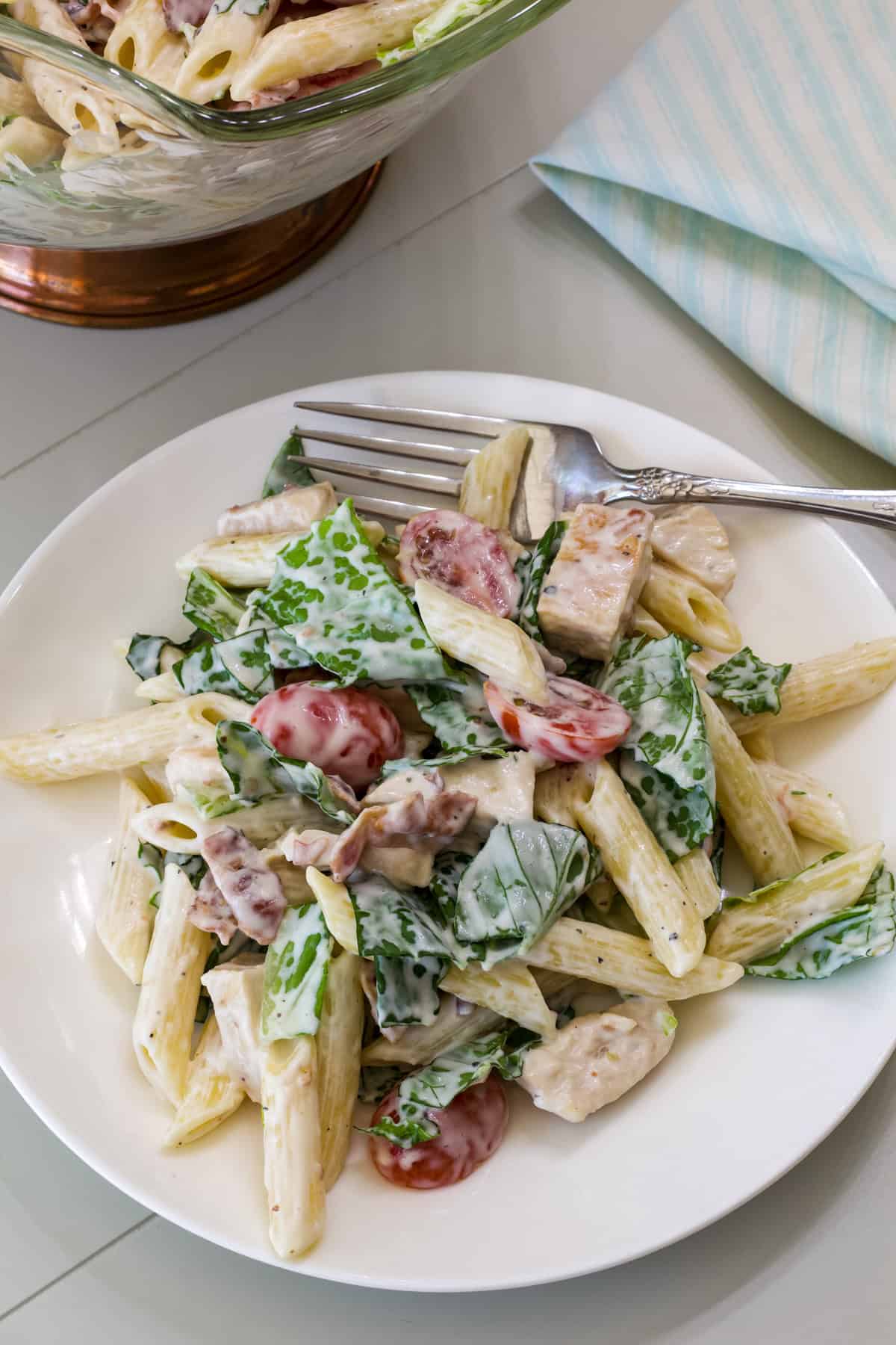 Overhead shot of one serving of Chicken BLT Pasta Salad on a white plate.