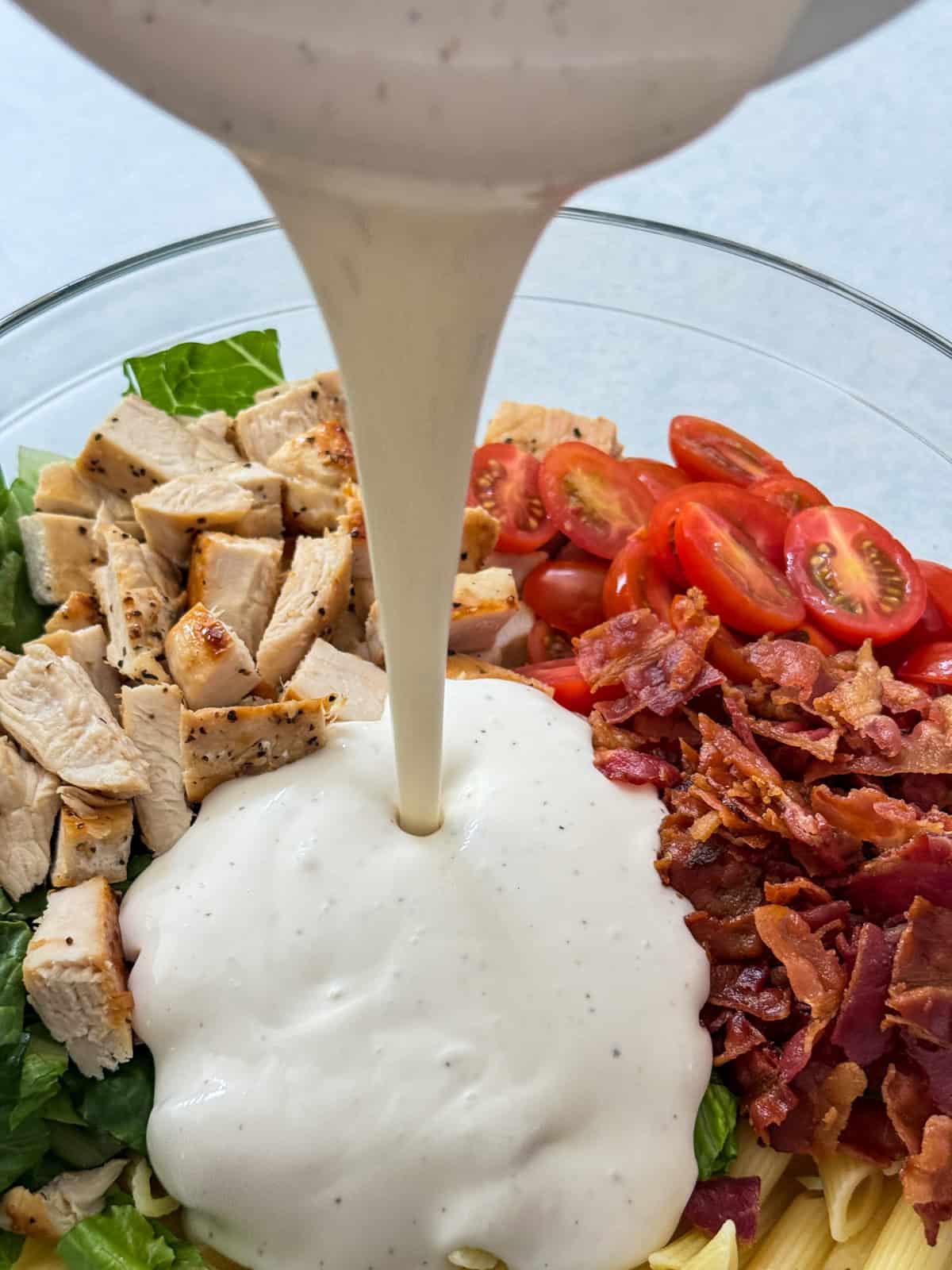 All of the ingredients in a mixing bowl and the ranch mixture being poured into it.