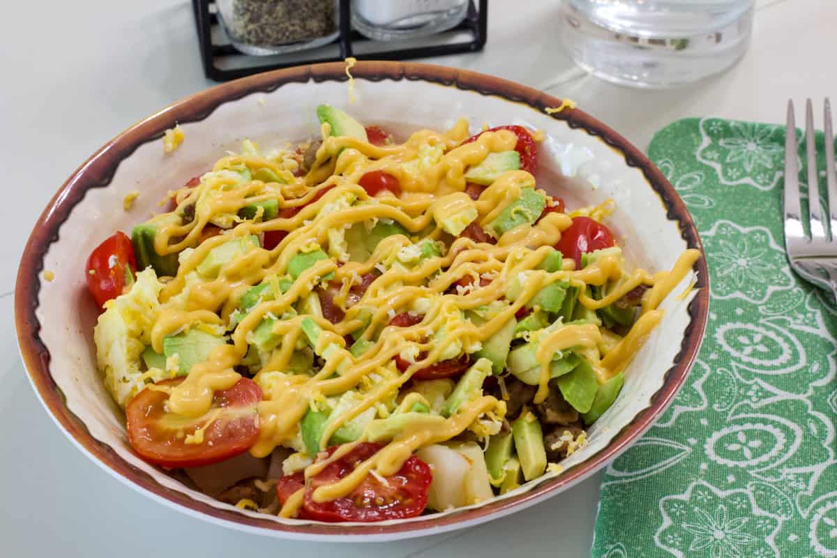 Side view of one sausage, potato,egg and veggie burrito bowl.