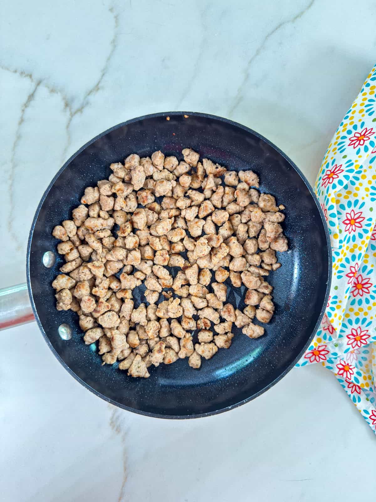 A small skillet with turkey sausage crumbles in it.