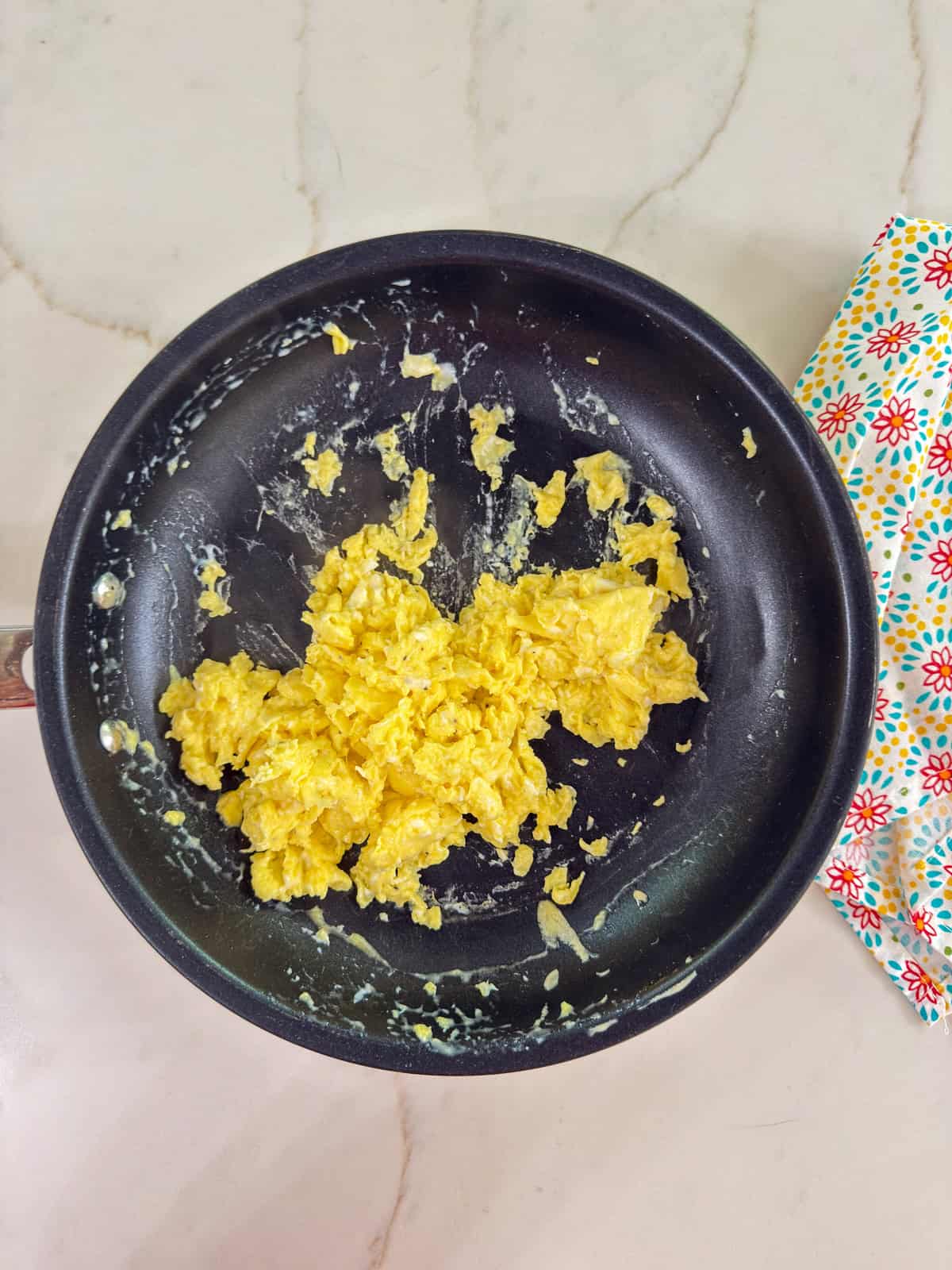 A nonstick skillet with cooked scrambled eggs in it.